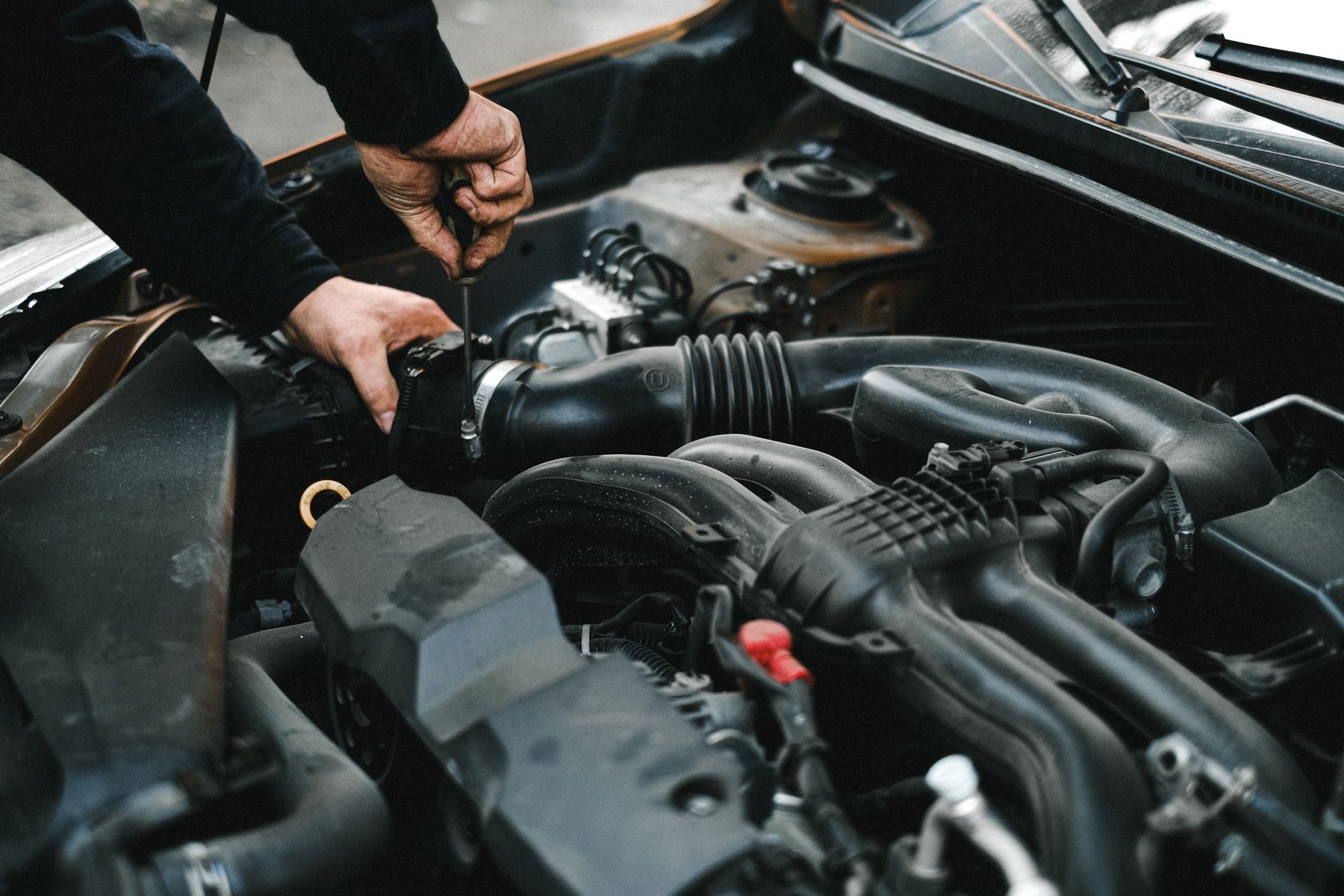 Technician inspecting a vehicle engine to assess whether a tow is needed